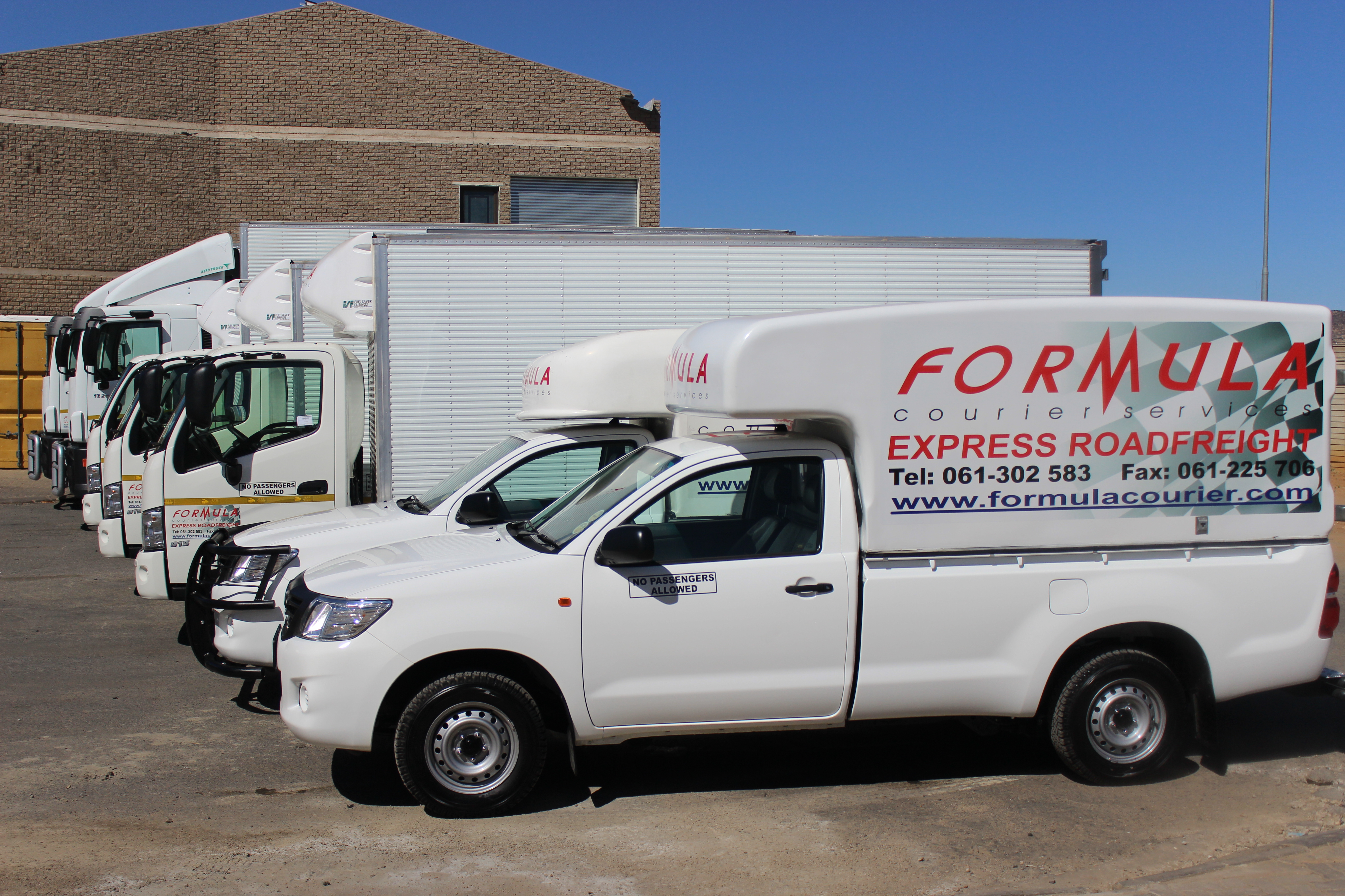 The Formula Courier Services fleet of branded vehicles lined up outside the depot